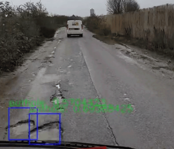 Photograph of a road in Swindon with Ai green boxes ont he floor picking up potholes from the moving vehicle the camera is attached to