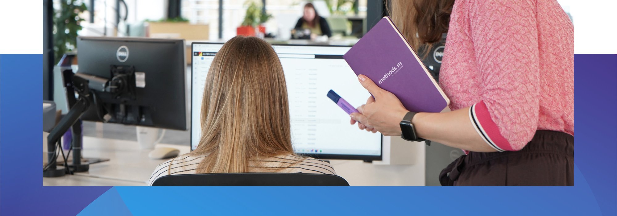 Decorative photo of a Methods employee assisting another employee working on computer in the Methods office