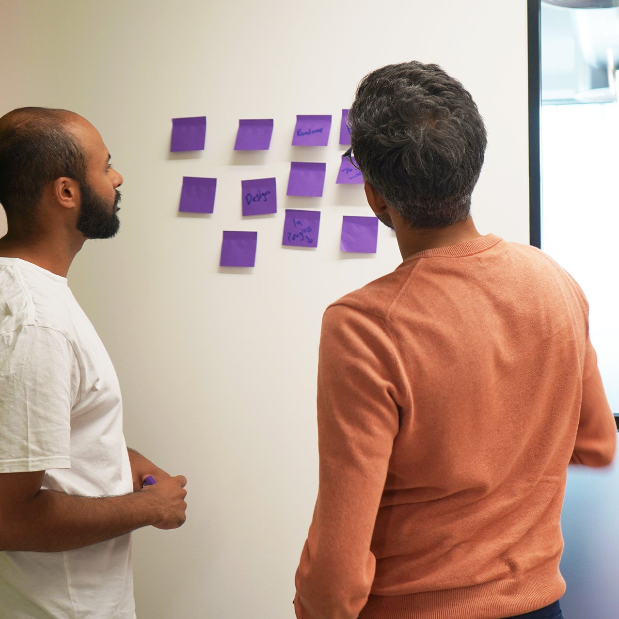 Decorative photo of Methods employees brainstorming with post-it notes on the office white walls