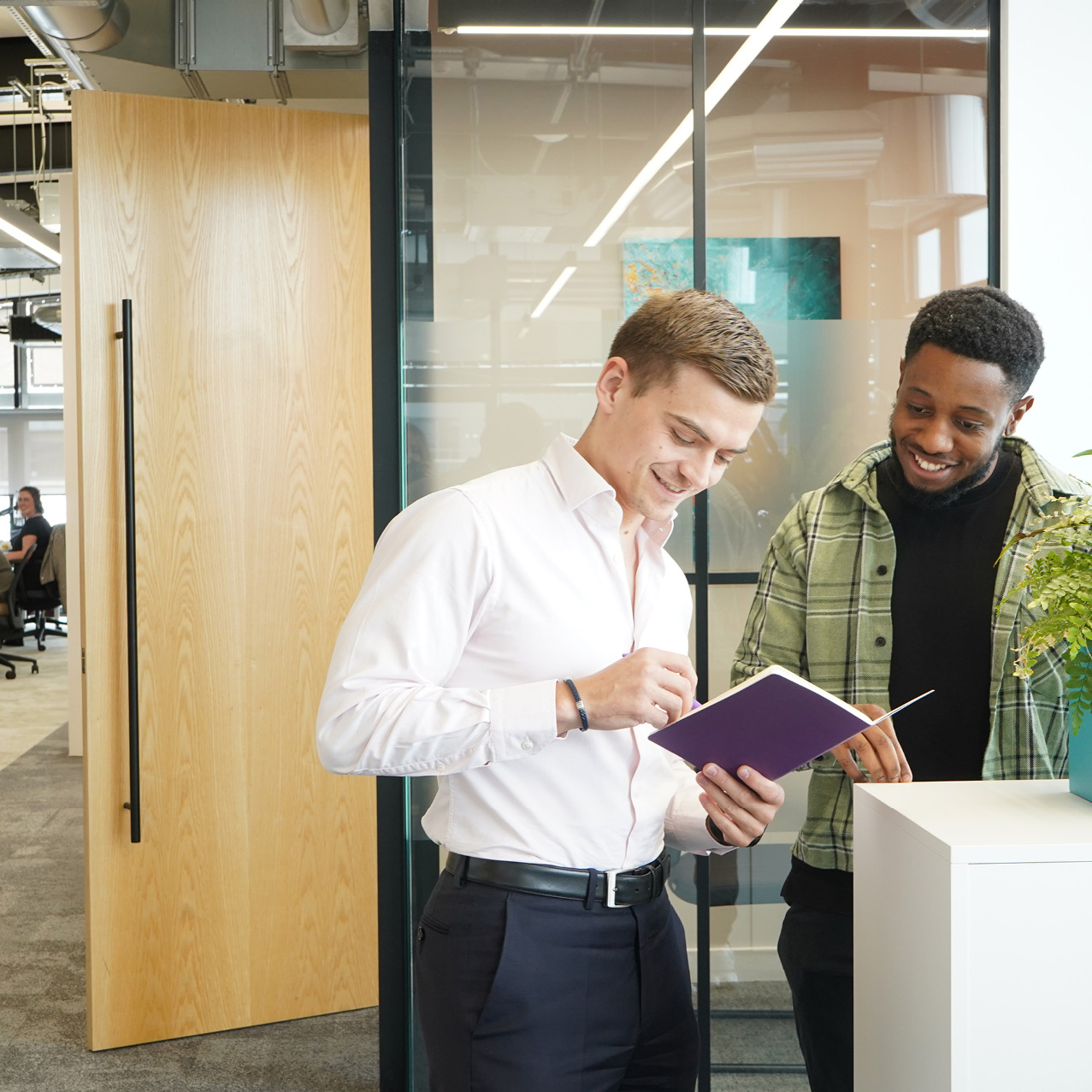 Decorative photo of Methods employees standing together and reading objectives from a note book in the office